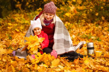 Mom and her daughter spending weekend, picnic in the autumn forest together. Mother and child relations