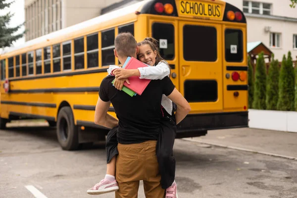 first day at school. father leads a little child school girl in first grade