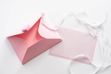 Beyaz arka planda mektup ve zarfın düz bir görüntüsü vardı. Düğün davetiyesi mi yoksa pembe güllü aşk mektubu mu? Sevgililer günü ya da anneler günü tatil konsepti, üst manzara, düz konum, genel görünüm.
