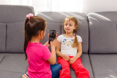 Çevrimiçi yayın vlog kanalı. Kız kardeşler sosyal ağ hesabı için komik fotoğraflar çekerler. Boş zaman ve eğlence. Sosyal ağlar konsepti. Sosyal ağlar için fotoğraf çeken kız arkadaşlar