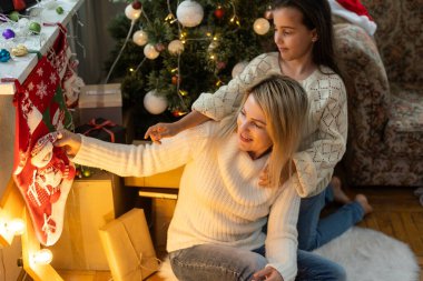 Mutlu bir annenin kızına sarılmasının yakın çekimi, rahat bir evde Noel havası.