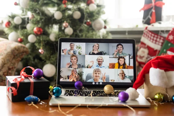 Family video call with kid presenting gift by remote chat laptop computer screen on Merry Christmas table holiday background. Xmas online virtual family party celebration, Happy New Year videocall.