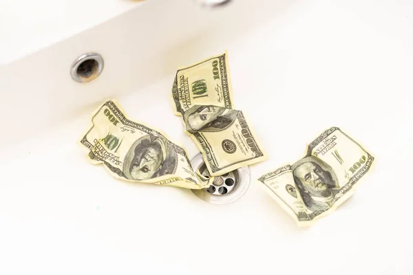 Money is thrown away in the sink. This photo concept illustrates the financial condition of a business that is failing or going bankrupt so that it only wastes money without results.
