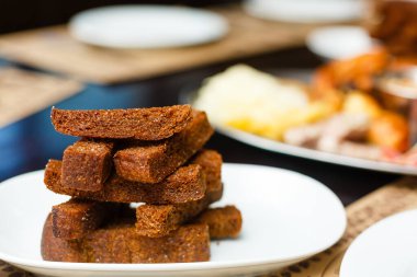 Beyaz tabakta çavdar ekmeği kızartılmış çubuklar. Aperatifler, büfe masasında atıştırmalıklar.