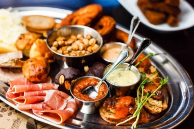 İspanyol mutfağı konsepti. Jamon dilimleri, sucuk, sosis. Soslu kâseler. Sosu da yanında olsun. İtalyan pastası. Avrupa gurme karışımı