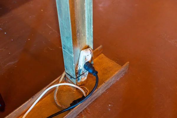 The extension power strip, power cord old and damaged on the construction site outdoor. Extremely dangerous, not safe if in use. Should be replaced. unsafe workplace