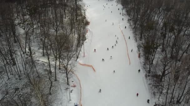 スキーやスノーボーダーは週末にスキーリフトでスキー場でスキーをします 冬の厳しい日にスキー場のスキー場やスノーボーダーと一緒に雪の上を飛ぶドローン ドローンビュー — ストック動画