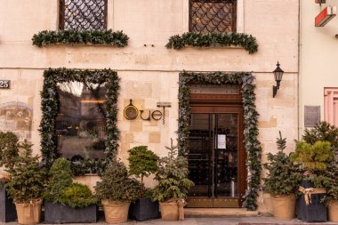 Noel sokak dekoru. Şık bir Noel çelengi, mücevherlerle süslenmiş boş bir tahta ve şehir sokaklarındaki kırsal ahşap kapılı bir pano. Metin için boşluk.