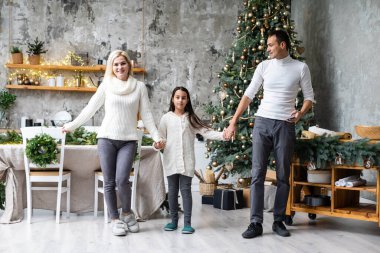 Mutlu Noeller ve mutlu tatiller. Anne, baba ve kız Noel ağacı süslüyorlar.