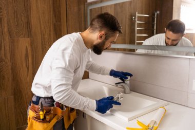 Profesyonel tesisatçı, üniformalı erkek işçi yeni daireye lavabo ve su borusu kuruyor..