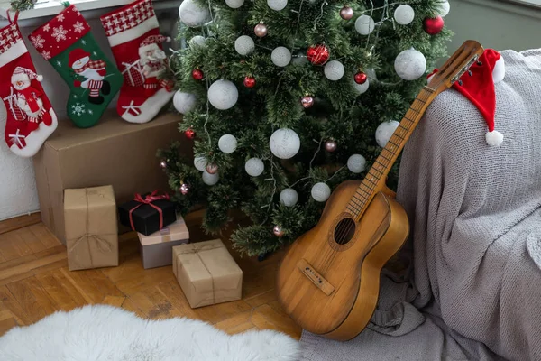 Gifts and presents under the xmas tree. Christmas tree with christmas decorations and christmas lights and acoustic guitar on background