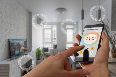 Ekranda akıllı ev yazılımı uygulaması olan cep telefonuna odaklan, dijital cihazlı kablosuz hafif müzik sıcaklık düzenlemesi, klima iklim kontrolü, iot, sanal asistan.
