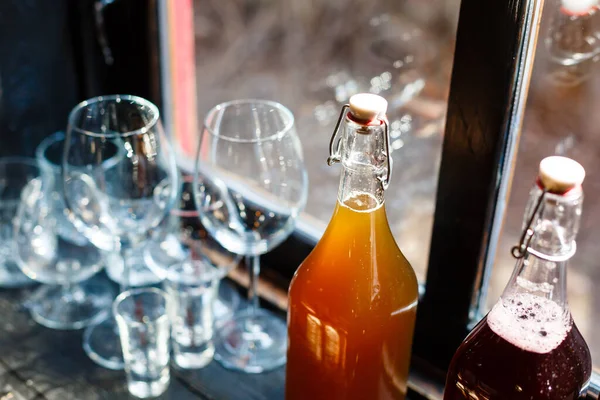 Restaurant, cafe or bar counter. Wine glasses, shot glasses, glasses for juice and water. Two bottles with non alcoholic party drinks. Beverages made of orange and red berries