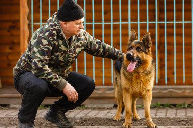 Adam köpeği etkiliyor, itaatkar ve sevgi dolu köpek, esir köpekler kafalarını parmaklıklardan çekiyor, genç adam köpeği besliyor, adam eğitiyor.