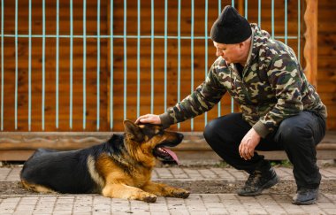 Adam köpeği etkiliyor, itaatkar ve sevgi dolu köpek, esir köpekler kafalarını parmaklıklardan çekiyor, genç adam köpeği besliyor, adam eğitiyor.