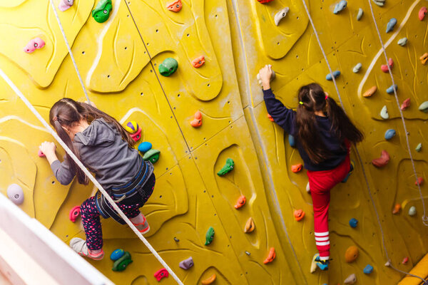 Two little girls climbing a rock wall