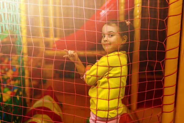 little girl on playground climbing in net
