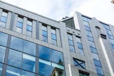 Pencereleri ve gri duvarları olan bir bina. Pencereler ışığı yansıtıyor