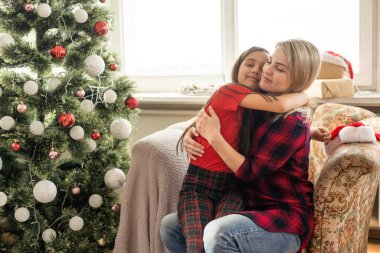 Mutlu bir annenin kızına sarılmasının yakın çekimi, rahat bir evde Noel havası..