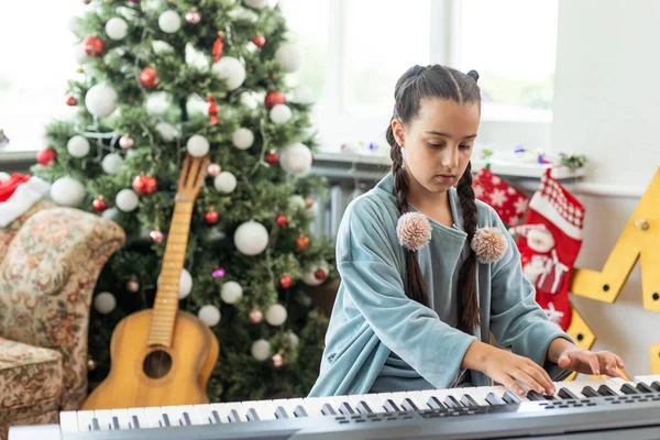 愛らしい少女大晦日クリスマス ツリーの背景には ピアノを弾く — ストック写真