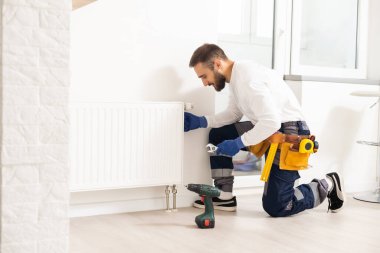 man repairing radiator with wrench. Removing air from the radiator.