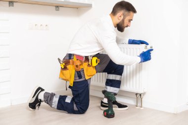 man repairing radiator with wrench. Removing air from the radiator.