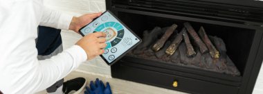 Tablette akıllı ev kontrolü. Arka planda oturma odasının içi..