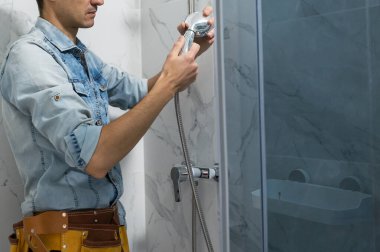 Tesisatçı banyoya duş kabini kuruyor..