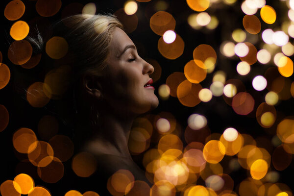 Christmas. Beautiful smiling woman. Manicure nails. Makeup. Healthy long hair style. Elegant lady in red dress over christmas tree lights background. happy new year. High quality photo