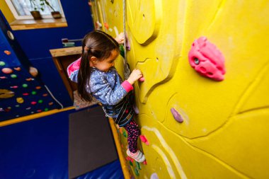 Küçük kız kaya duvarına tırmanıyor..