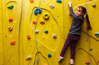 küçük kız kapalı bir kaya duvarı tırmanışı