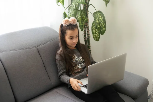 E-education, online lessons and courses for schoolers. Joyful teen girl looking at laptop screen, watching online lesson or listening to tutor, home interior, copy space.