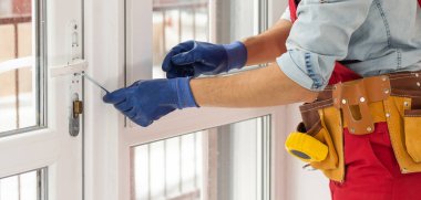 Bir çerçeve eve plastik montajı, inşaatçı bir tornavidayla pencere çerçevesini yamaçlara vidalar. yakın plan