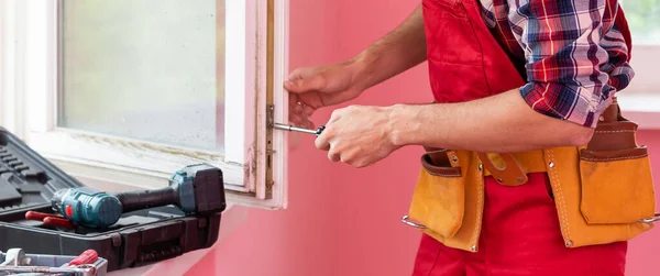 Young worker repairing window in flat