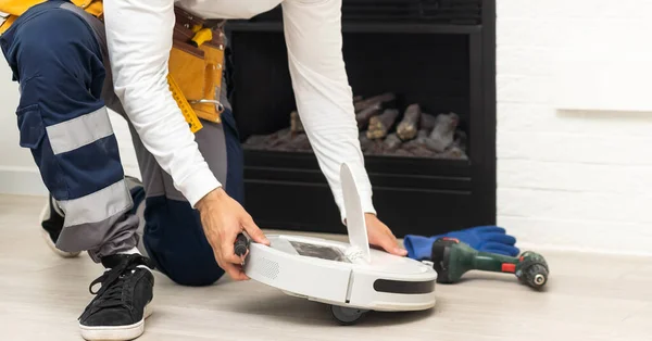 Repairman changing batteries on robotic vacuum cleaner. Repairing robot cleaner