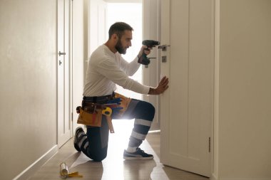 High Angle View Of Male Carpenter With Screwdriver Fixing Door Lock.