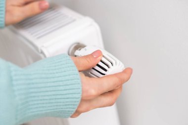 Kazaklı bir kadının yakın çekimi beyaz duvarın arkasındaki akünün üzerinde ellerini ısıtıyor. Makro kadın eli fotoğrafı, kopyalama alanı. Kışın gaz tasarrufu kavramı. Avrupa 'da gaz krizi.