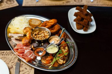 İtalyan antipasti şarap atıştırmalıkları masada. Kırmızı şarap bardakları, peynir çeşitleri, bruschetta, zeytin, prosciutto, açık hava partisi