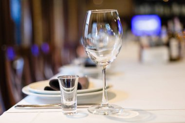 Mor yer paspasları ve boş şarap kadehleriyle akşam yemeği için hazır beyaz porselen sofra takımlarını kapatın. Masa ayarları misafirler için evde ya da restoranda bekler