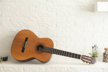 Minimalist iç tasarım konsepti. Gri tekstil koltukta akustik gitar. Dairenin geniş odasındaki ahşap desenli lamine döşeme. Arkaplan, kopyala boşluk, kapat.