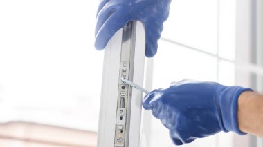 Bir çerçeve eve plastik montajı, inşaatçı bir tornavidayla pencere çerçevesini yamaçlara vidalar. yakın plan