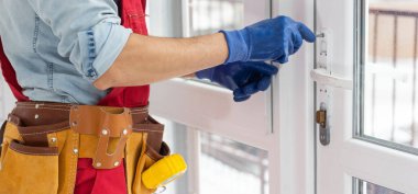 Bir çerçeve eve plastik montajı, inşaatçı bir tornavidayla pencere çerçevesini yamaçlara vidalar. yakın plan