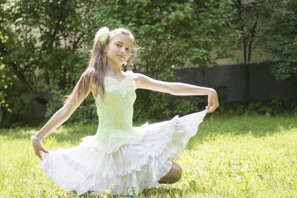 Tiener meisje zit in lichte jurk op het gras — Stockfoto