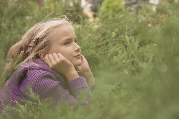 Menina agradável sentado no arbusto ao ar livre — Fotografia de Stock