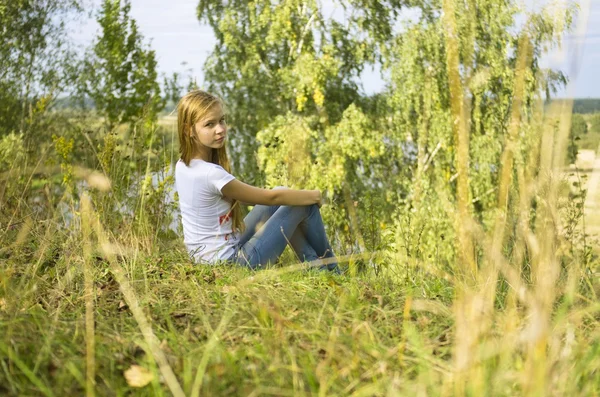年轻姑娘坐在草地 — 图库照片