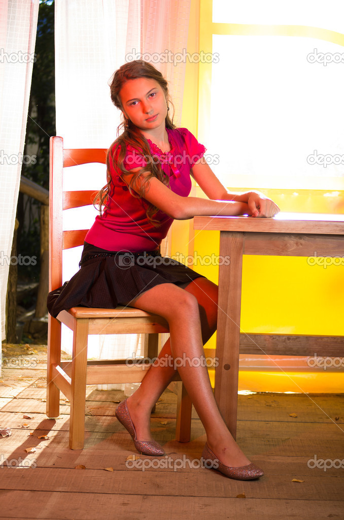 young girl sitting near wooden table