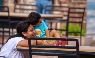 Oğluyla parkta bankta oturan genç Hintli kadın. 