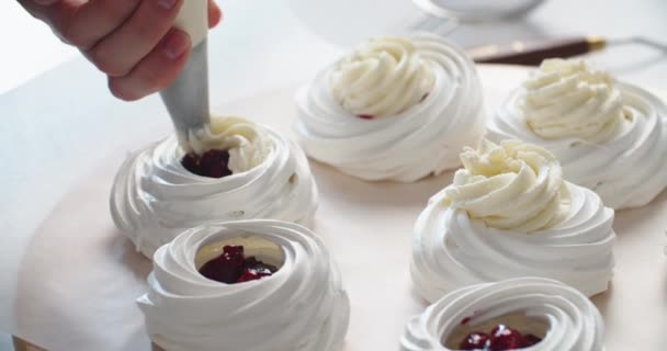 Giovane pasticcere donna riempie brownies crema con sacchetto di pasticceria. Processo di fabbricazione della torta Anna Pavlova. Primo piano — Video Stock