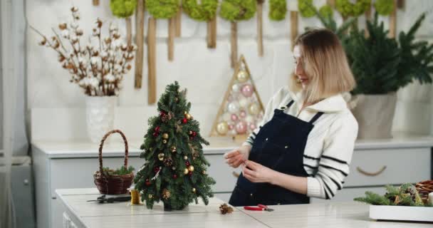Floristin bei der Arbeit: Wie man aus Thuja-Zweigen schönen Weihnachtsschmuck in Tannenform macht. — Stockvideo