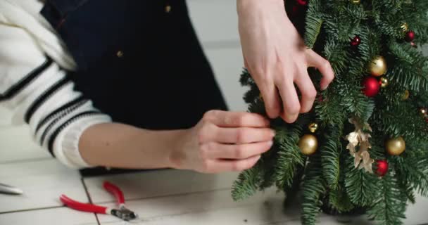 Großaufnahme einer Frauenhand, die einen Weihnachtsbaum schmückt und bereit ist, Heiligabend zu feiern. Glück, Weihnachten, Stimmung, Hilfe. — Stockvideo